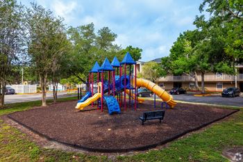 a playground with a blue and yellow slide in a park